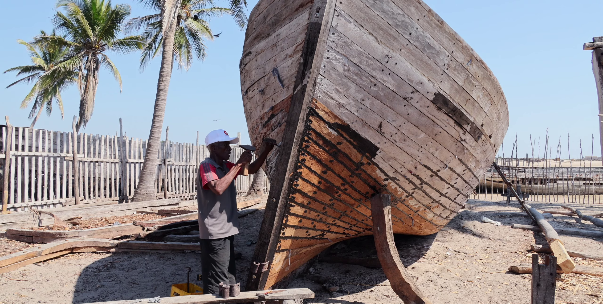 Artisan travaillant sur la carène d'un boutre au chantier naval de Belo sur Mer