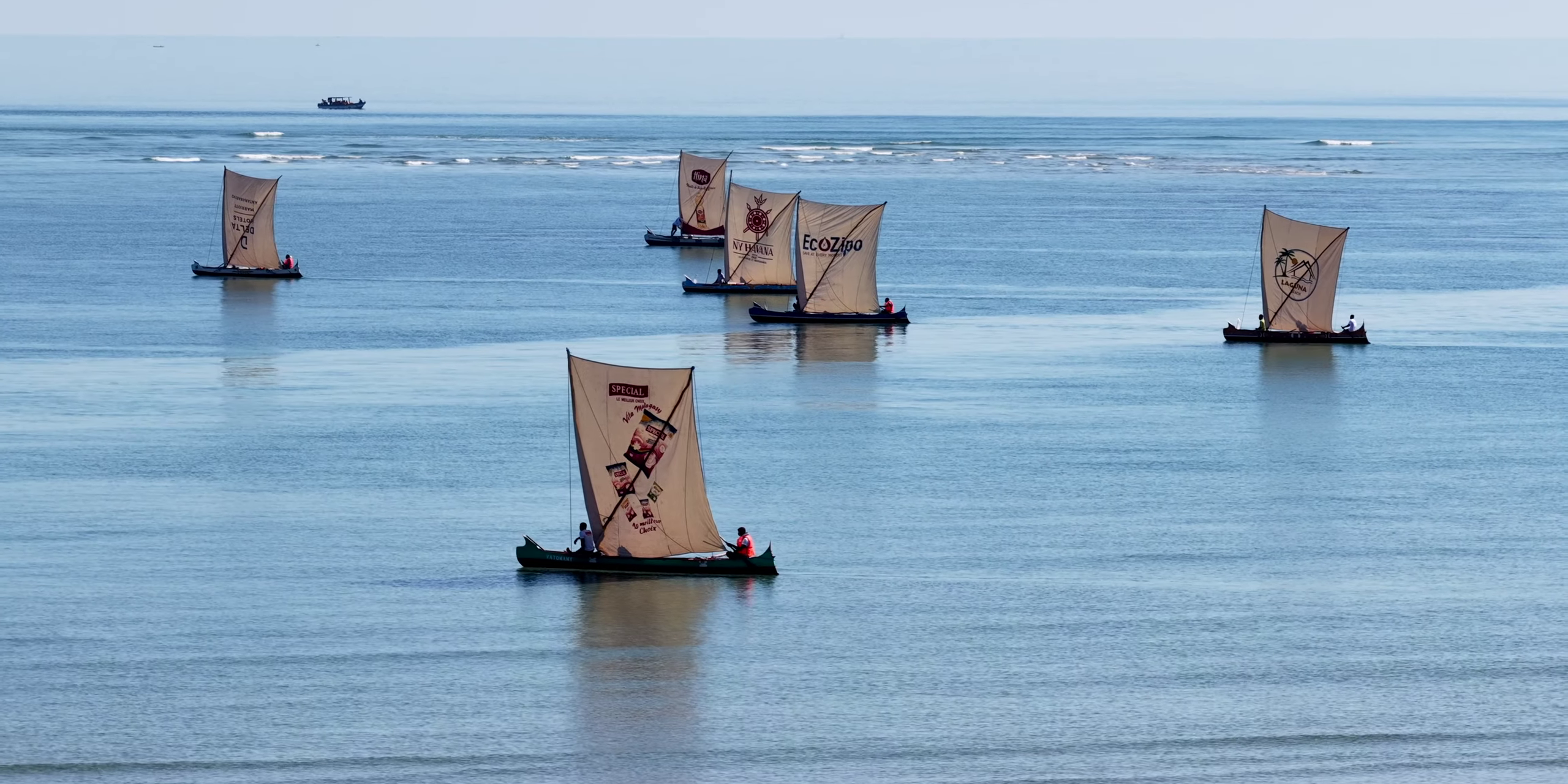 Pirogues à voiles traditionnelles en régates sur mer calme bleutée