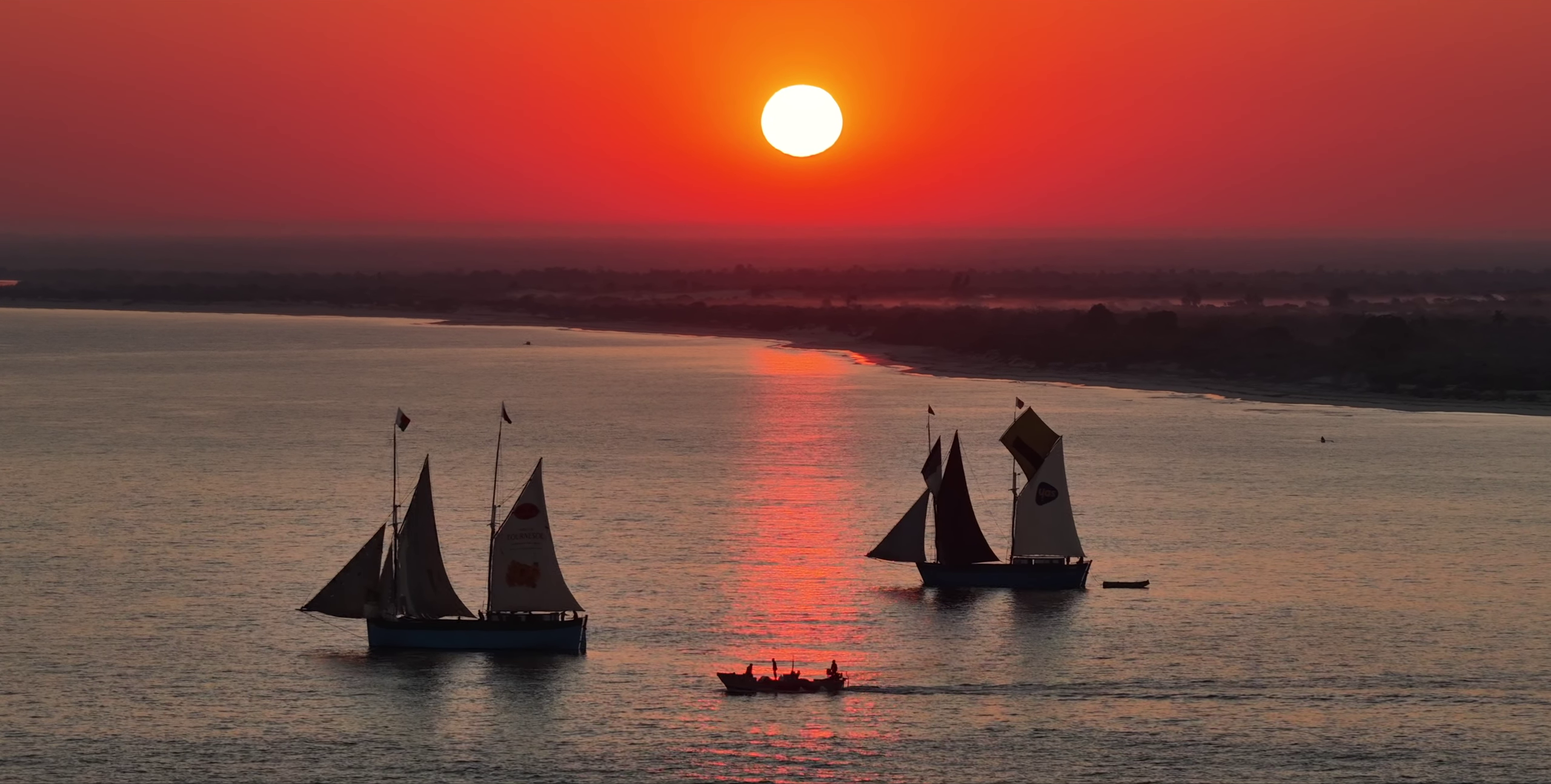 Boutres et goélettes naviguant au coucher du soleil rouge flamboyant — côte de Belo sur Mer